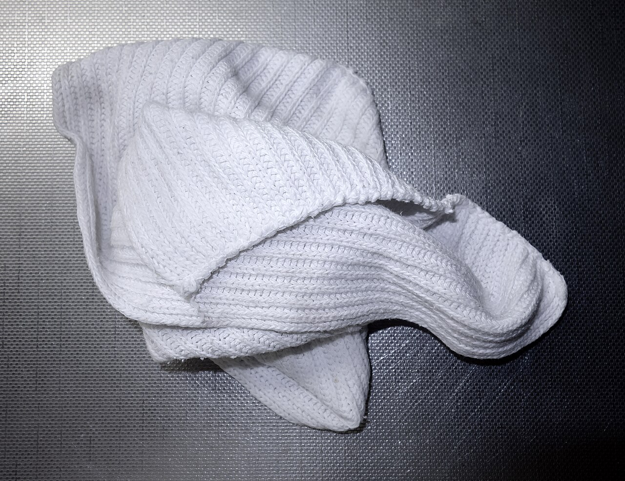 Folded white cleaning cloth on a steel surface